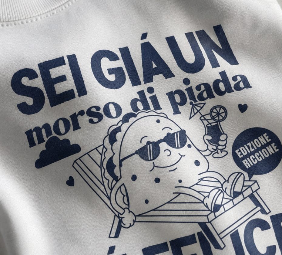 Warm brown Arlecchino Hotel t-shirt print worn in a seaside terrace setting with piadina and summer drinks