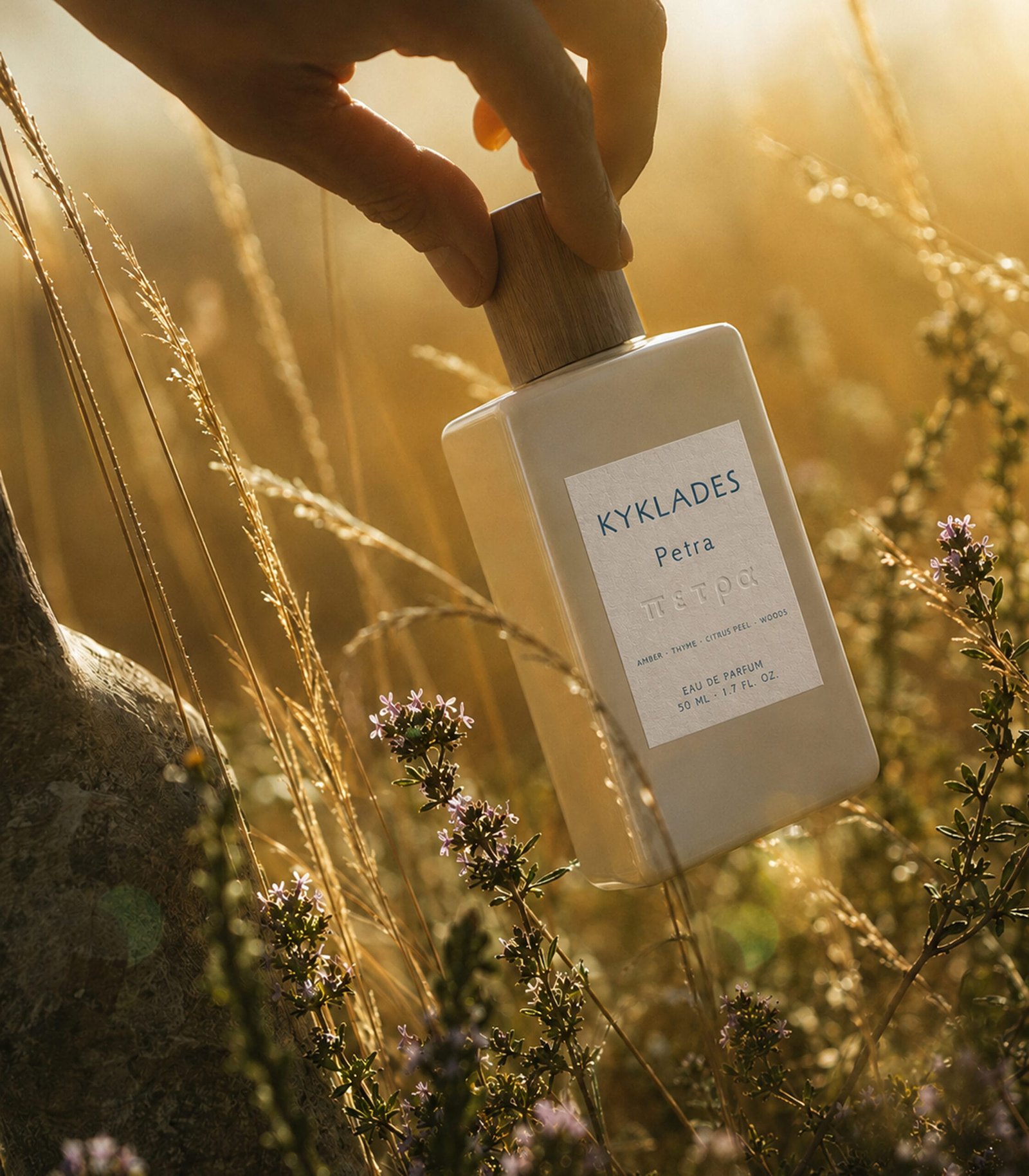 Hand holding KYKLADES Petra perfume in golden-hour Mediterranean light